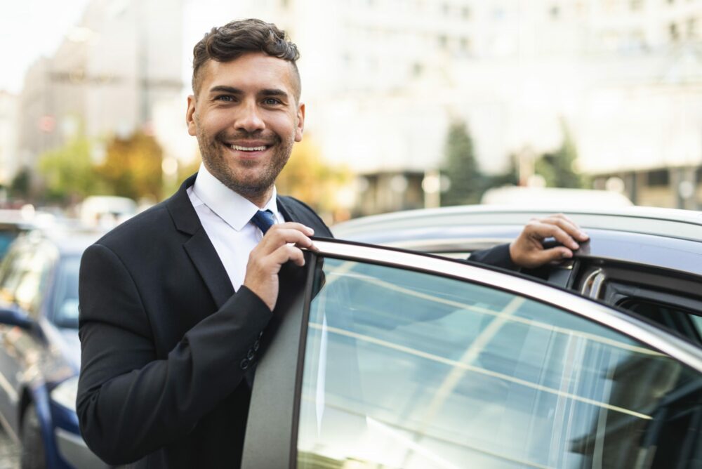 business man with car, smiling after calculating his self-employed mileage deduction