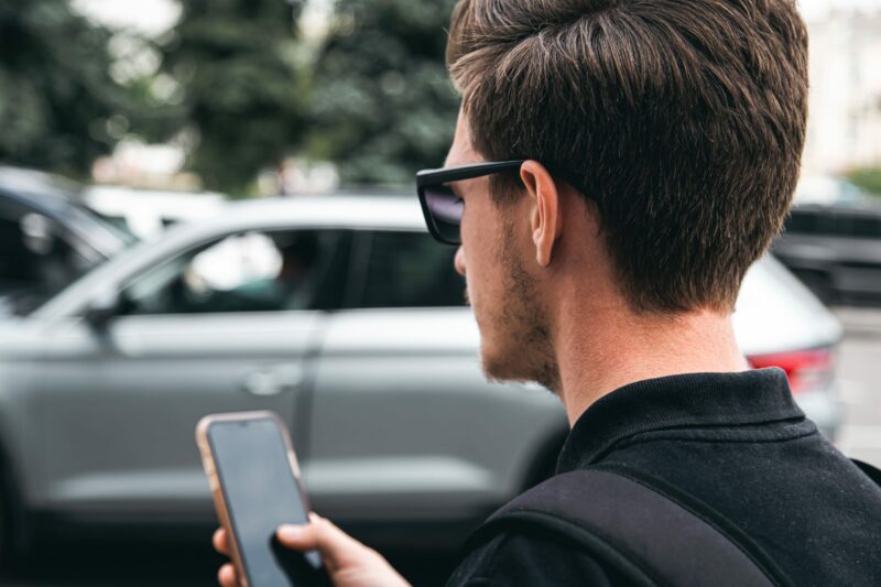 man with smartphone and car creating a simple mileage log